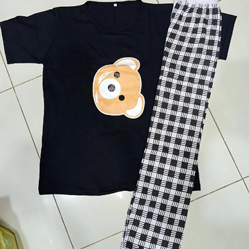 Black t-shirt with a bear graphic and black and white checkered pants on a tiled floor.