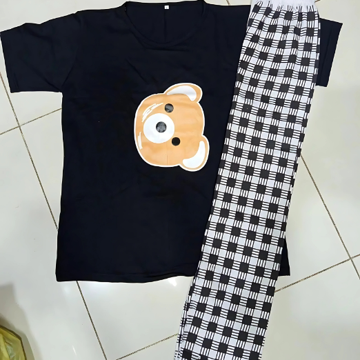 Black t-shirt with a bear graphic and black and white checkered pants on a tiled floor.