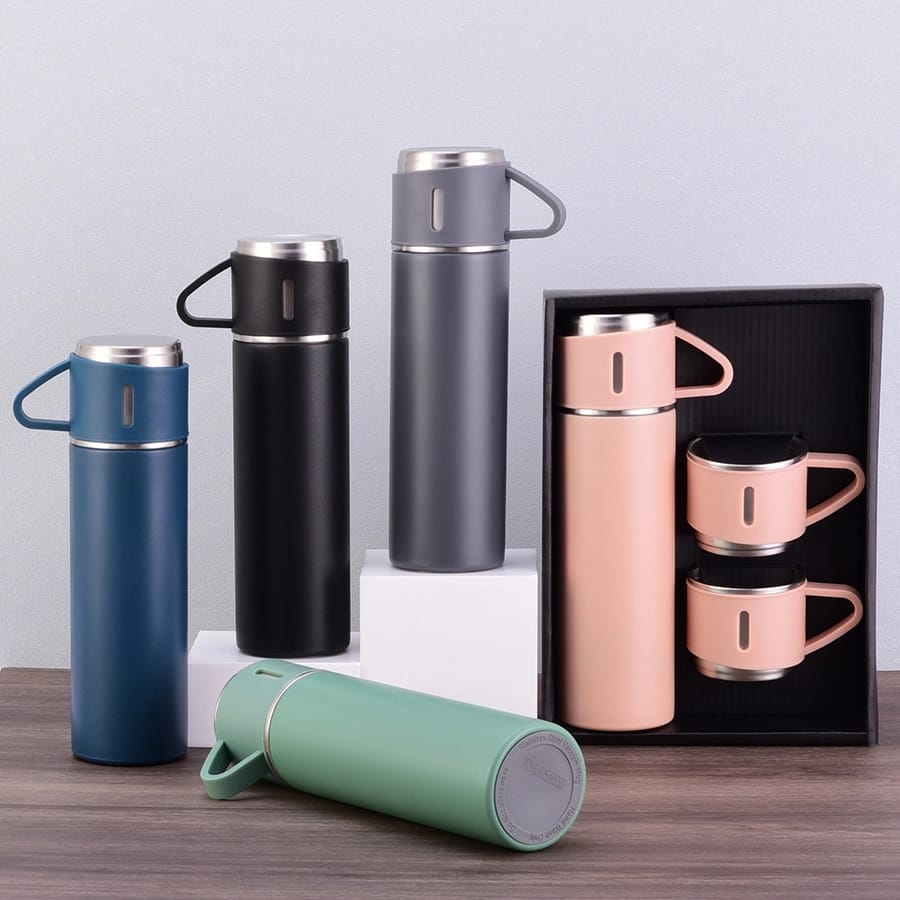 Collection of stainless steel thermos bottles and mugs on a wooden surface with a light gray background.