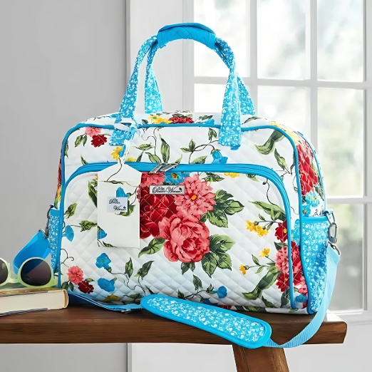 Floral patterned duffel bag with blue accents on a wooden surface.