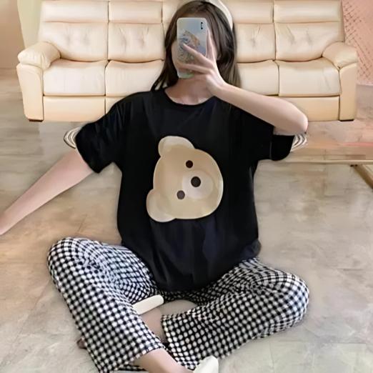 Black t-shirt with a bear graphic and black and white checkered pants on a tiled floor.