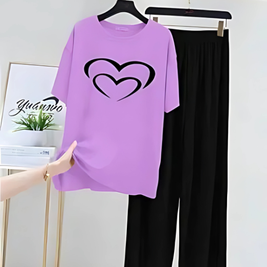 Purple t-shirt with heart design and black pants on a hanger against a white wall.