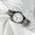 Silver wristwatch with a white face on a white fabric background