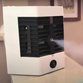 White and black air cooler on a table with a blurred background