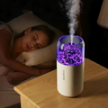 Woman lying in bed with a diffuser emitting steam on a wooden nightstand.